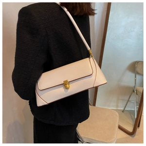 Close-up of a white leather baguette bag with retro gold twist lock and brown edge dye