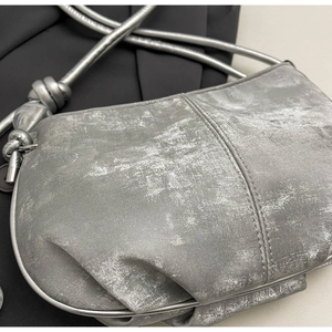 Close-up of metallic silver cloud bag showing vintage texture and knotted strap details