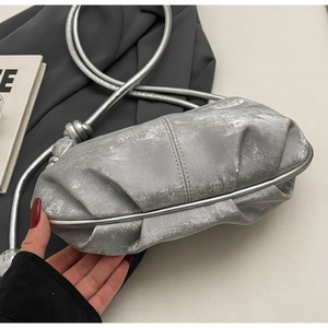 Detailed macro view of silver cloud crossbody bag featuring metallic texture and pleats