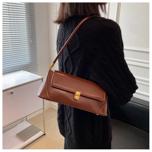 Detail showing the side view of a brown leather baguette bag with gold metal buckle