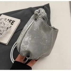 Detail of silver matte soft PU cloud bag with artistic metallic handle and clear sphere