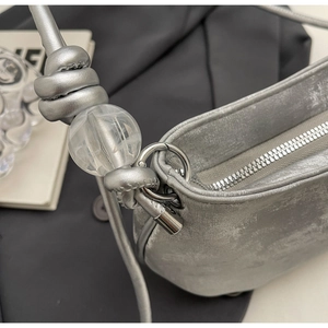 Detail of silver metallic purse with knotted strap and large transparent bead accent