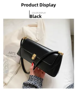 Close-up of black leather baguette bag featuring a sleek gold metal lock clasp