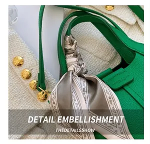 Detail of green litchi grain leather bucket bag with decorative silk scarf on handle