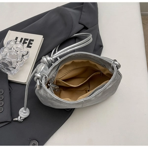 Detail view of silver pleated cloud bag with fabric lining and interior zipper pocket