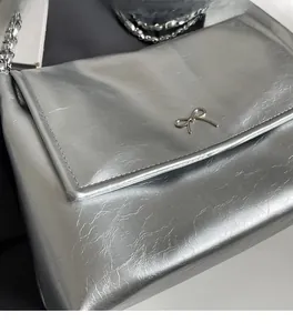 Close-up of silver tote bag showing metallic texture and decorative metal bow