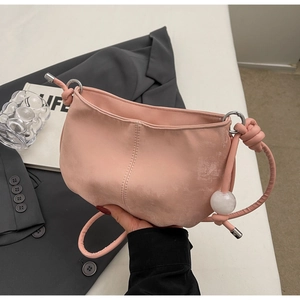 Detail of soft pink cloud-textured purse with knotted strap and elegant white pearl bead
