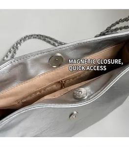 Detail of silver metallic tote bag showing magnetic closure and interior zip pocket