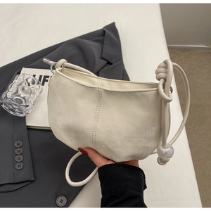 Detail of minimalist cream cloud bag featuring knotted strap and marble texture bead