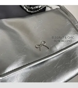 Close-up of silver crinkled leather tote bag featuring a delicate metal bow detail