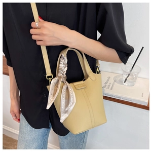 Detail of beige bucket bag with lychee texture, silk scarf and adjustable leather strap