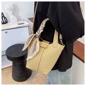 Detail of beige bucket bag with litchi grain leather and scarf-wrapped handle