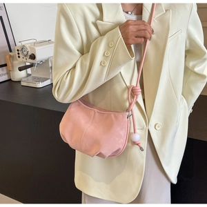 Detail of pink hobo bag with unique knot strap and white bead charm on a model