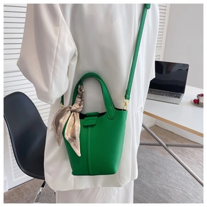Detail of green lychee leather bucket bag featuring a decorative printed silk scarf handle