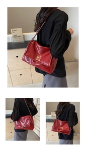 Detailed macro view of the glossy red leather tote with metallic bow and chain strap
