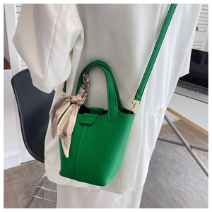 Detailed close-up of emerald green bucket bag with lychee grain leather and silk scarf wrap
