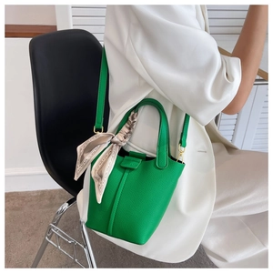 Detail of green litchi grain leather bucket bag with silk scarf on the top handle