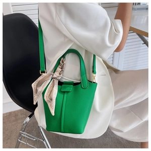 Detail of green litchi grain leather bucket bag with decorative silk scarf on handle