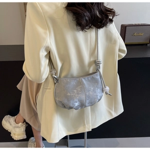 Detail of silver cloud bag with knot strap and clear beads worn over a beige blazer