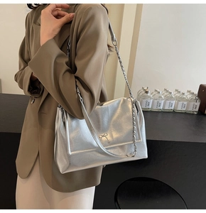 Close-up of a silver PU leather shoulder bag featuring a stylish metallic bow buckle