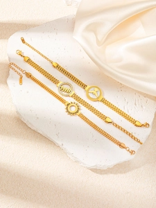 Vue détaillée de trois bracelets dorés avec breloques soleil, feuille et oiseau
