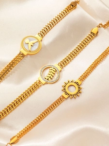 Gros plan détaillé de bracelets cubains dorés avec breloques soleil, feuille et ange