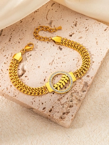 Vue macro d'un bracelet doré à maille tressée avec pendentif feuille de blé serti