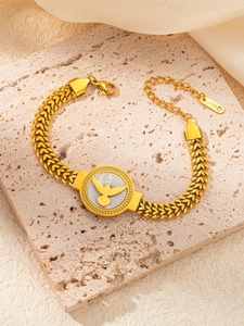 Détail du bracelet chaîne dorée avec motif d'oiseau sur nacre et pendentif en acier S.STEEL