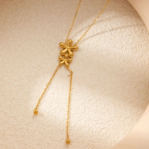 Detail of delicate gold necklace featuring double flower pendants and long tassels