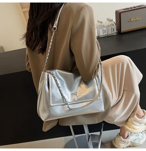Detail of silver metallic tote bag featuring a metal bow and chain patchwork strap