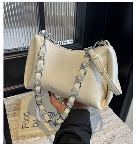 Détail du sac crème en cuir plissé avec bandoulière chaîne argentée élégante