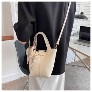 Detail of cream bucket bag with lychee texture leather and decorative silk scarf handle