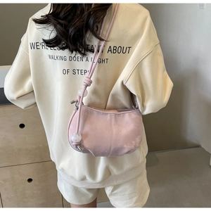Pink crescent cloud bag with bead detail worn by a model in a cozy indoor setting