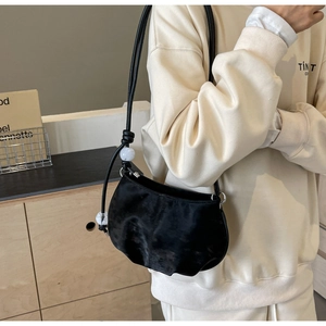 Detail of black suede shoulder bag featuring marble beads and knotted strap design