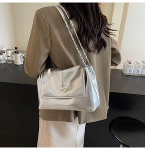 Detail of silver metallic shoulder bag with metal bow accent and chain strap