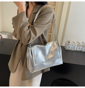 Detailed shot of silver metallic shoulder bag with metal bow buckle and chain strap