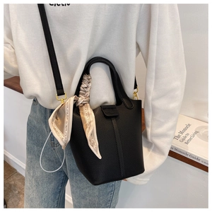 Close-up of black lychee leather bucket bag with decorative silk scarf and gold hardware