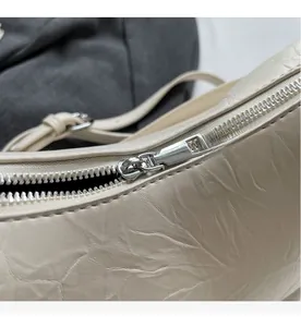 Détail de la fermeture éclair en métal argenté sur un sac à chaîne blanc cassé