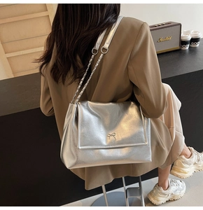 Macro shot of silver metallic tote with a bow metal clasp and chain shoulder strap