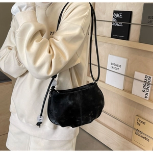 Detail of minimalist black cloud bag with thin rope strap and transparent bead ornaments