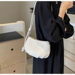 Detail of soft cream cloud bag featuring slim rope straps and decorative acrylic beads