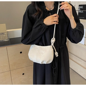 Detail of white half-moon crossbody bag with knot shoulder strap and pleated texture