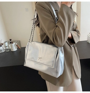 Detail of silver metallic tote bag with cracked texture and small metal bow detail
