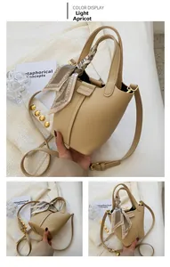 Detail view of apricot bucket bag featuring litchi grain leather and silk scarf handle
