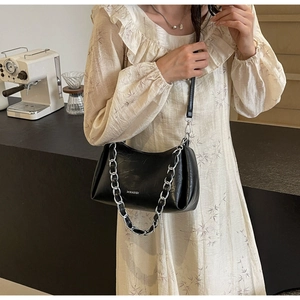 Sac sous le bras en cuir noir brillant avec grosse chaîne argentée sur un mannequin
