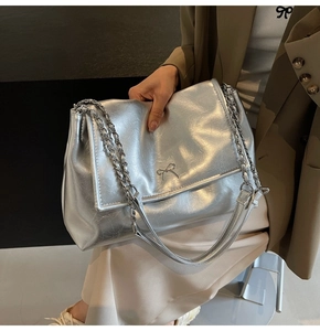 Detail of silver metallic tote bag with bow hardware and chain shoulder strap