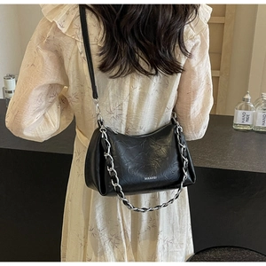 Détail du sac à bandoulière noir à texture plissée et chaîne en métal argenté