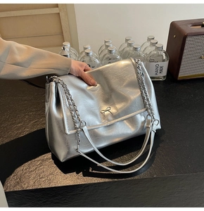 Detail of silver metallic tote bag with pleated texture and silver bow buckle embellishment