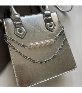 Détail du sac argenté avec texture craquelée et chaîne ornée de perles blanches