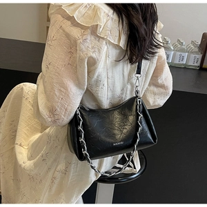 Détail d'un sac d'épaule en cuir froissé noir avec chaîne argentée et logo